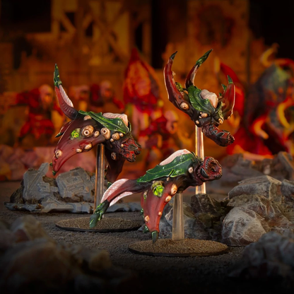 Three red and green multi-eyed flying Deadzone Nightmare Incursion Booster miniatures on clear stands over rocky terrain