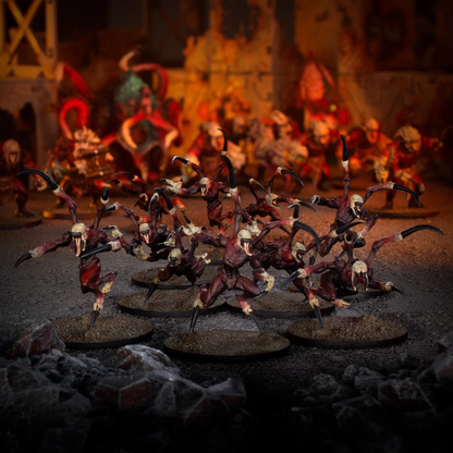 A group of detailed red and pale monster miniatures from the Deadzone - Nightmare Incursion Booster stand on bases in a dark, fiery, ruined environment with more creatures in the background