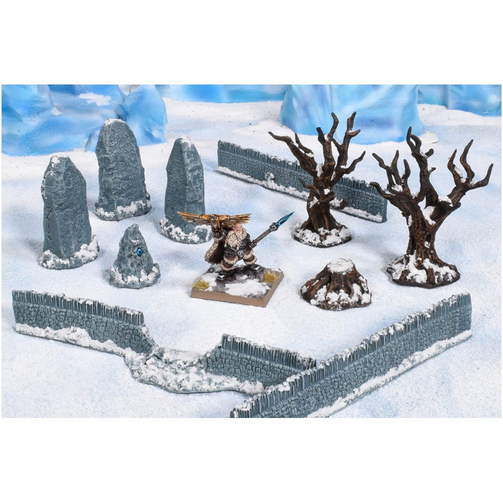 A miniature bearded warrior with a spear stands on snowy terrain, surrounded by stone monoliths, bare trees, stone walls and ice formations