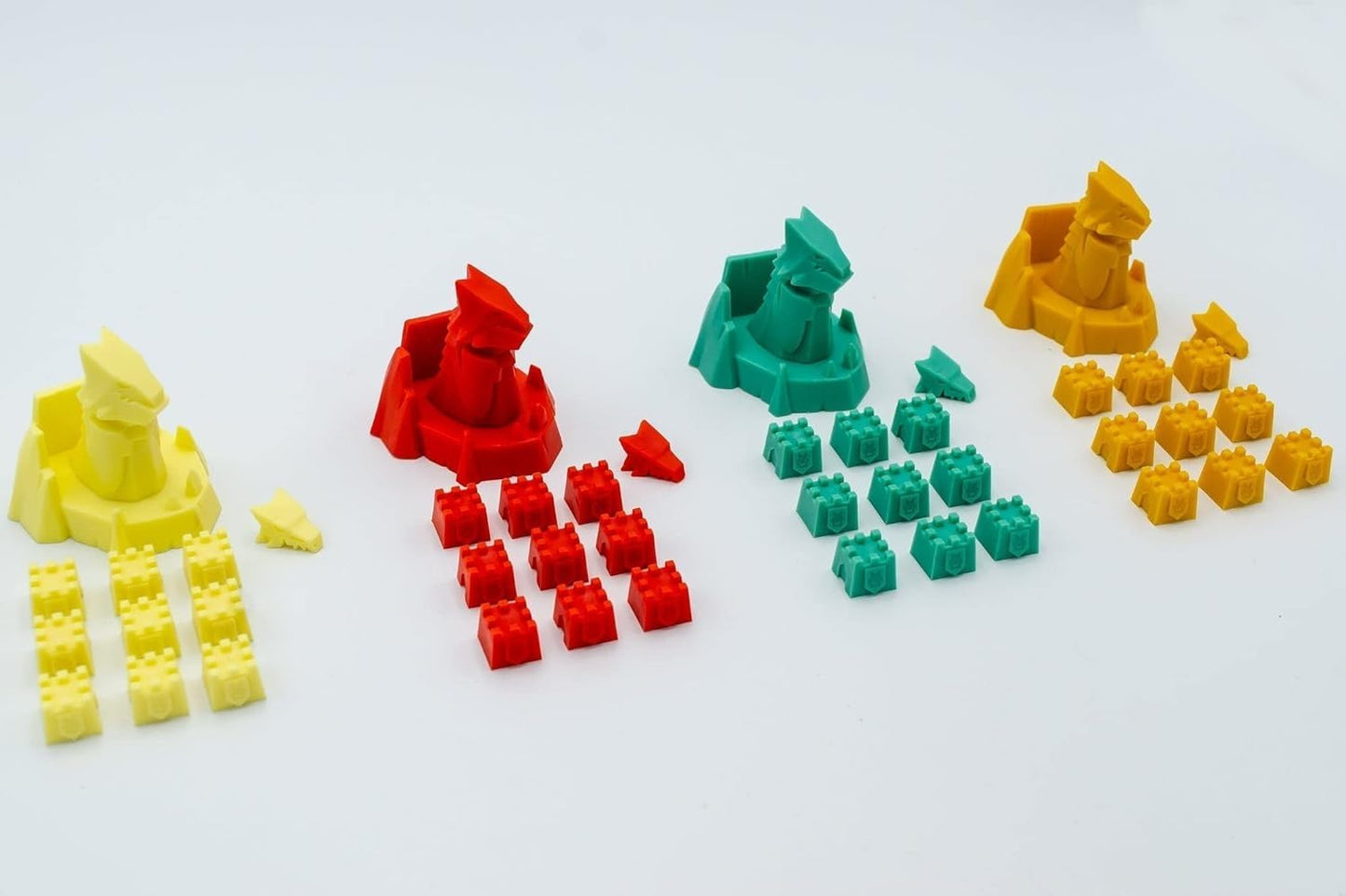 Board game pieces: yellow, red, and green dragon figures with matching castle tokens, neatly arranged on a white background.