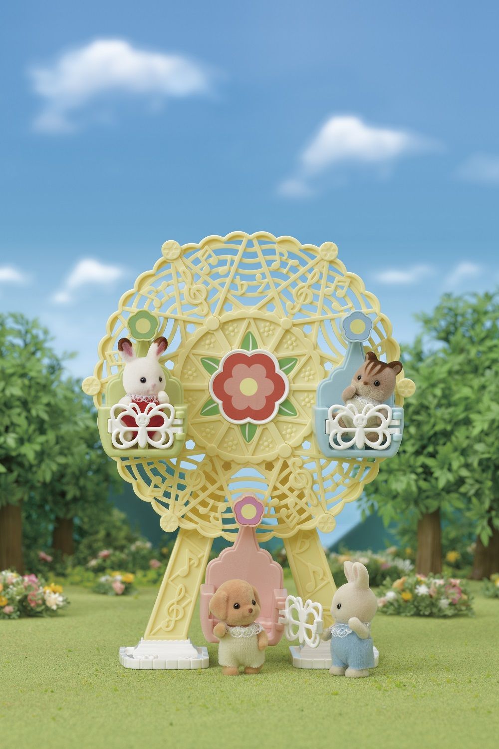 Flocked critter figures riding a yellow musical Ferris wheel toy in a sunny park scene