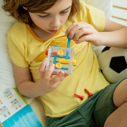 A child actively uses the clear Criss Cross Cube brainteaser, pushing a blue piece into the logic puzzle structure