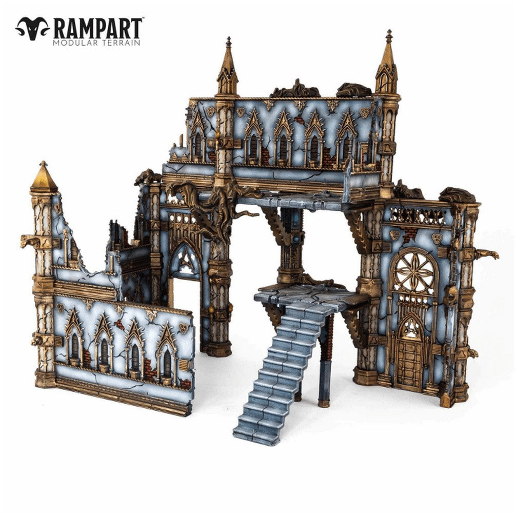 Modular tabletop terrain: a multi-level ruined gothic building with blue-gray walls, golden trim, archways, and stairs