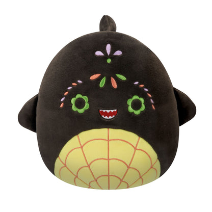 A black Squishmallow plush toy featuring a yellow spiderweb belly, green flower eyes, a toothed smile, and colorful embroidered floral patterns on its face