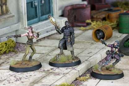 Three Fallout miniatures: a woman with a pistol/bat, a man with a large gun, and a woman aiming a pistol, posed in a ruined city.