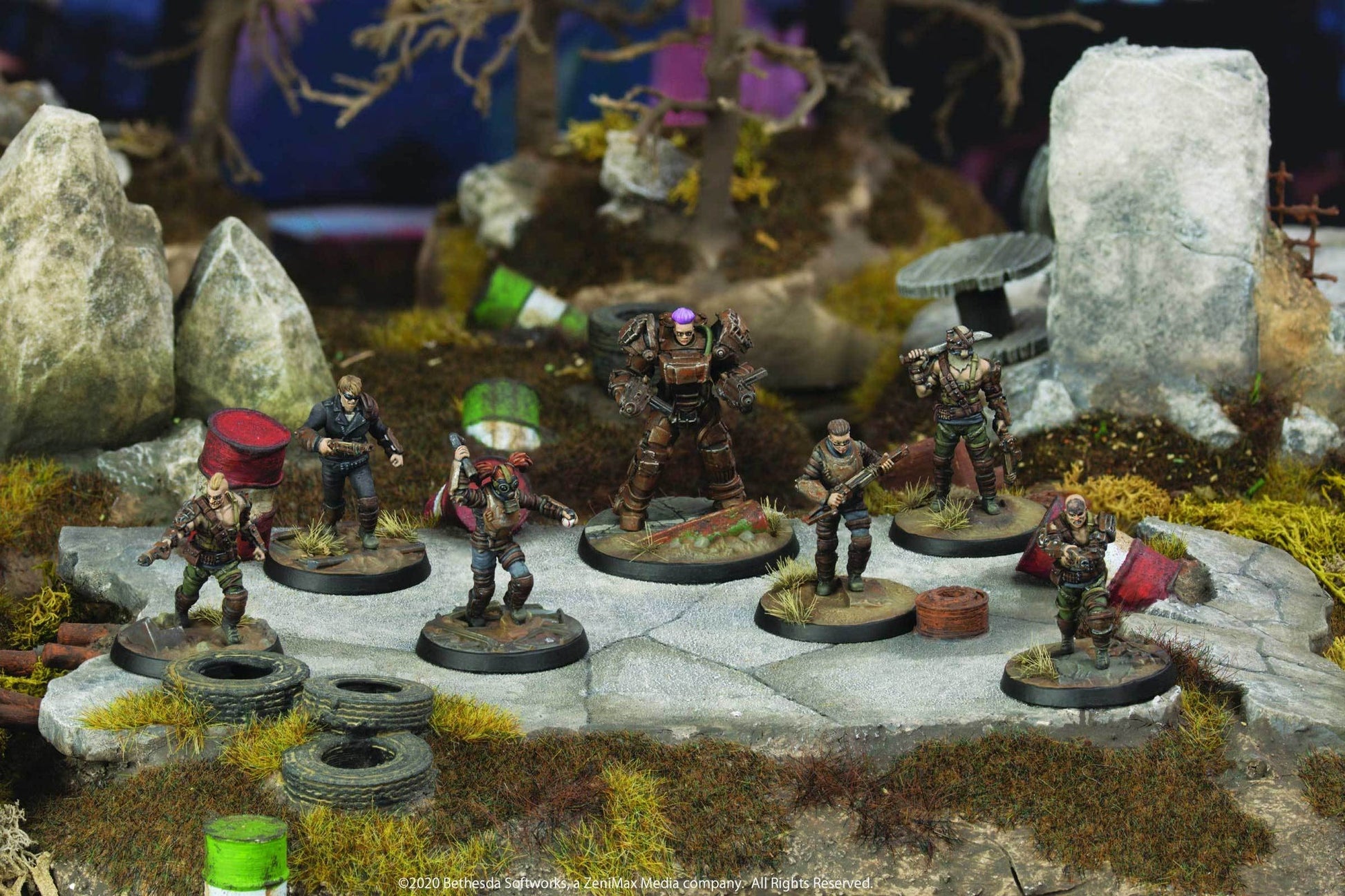Seven armed wasteland miniature figures, one in power armor, posed on a detailed rocky diorama