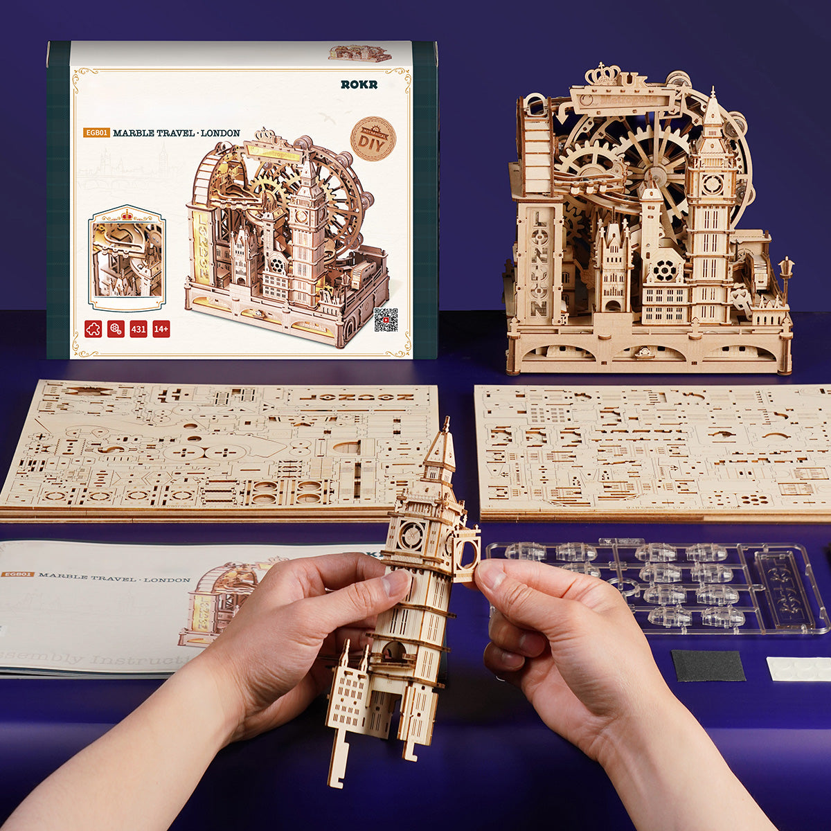 Hands assembling a detailed wooden 3D puzzle model of Big Ben, with the finished London kit displayed