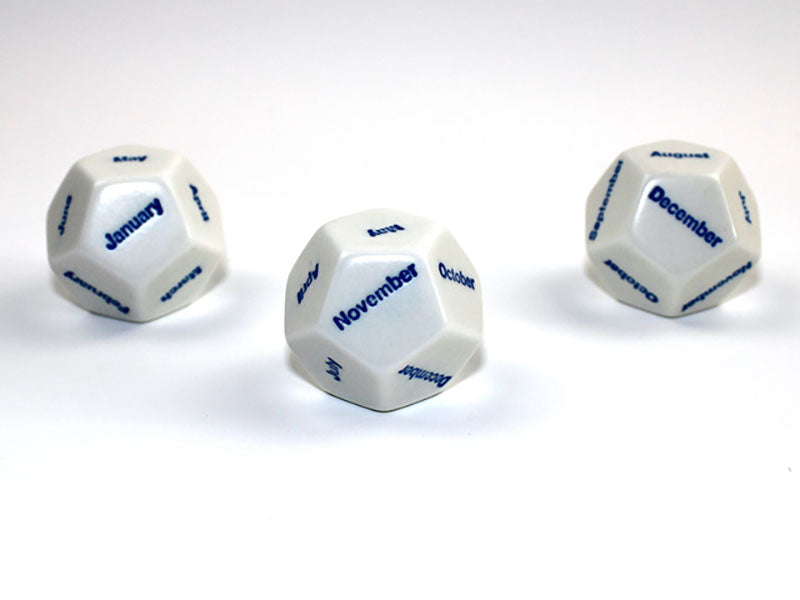 Three white 12 sided dice with blue Months showing on a white background