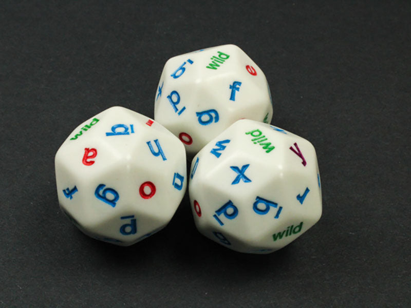 Three white 20-sided letter dice with blue consonants, red vowels, and green "wild" faces, clustered on a dark surface 
