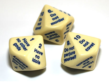 Three cream-colored dice with blue text showing the Ten Commandments scattered on a white surface 