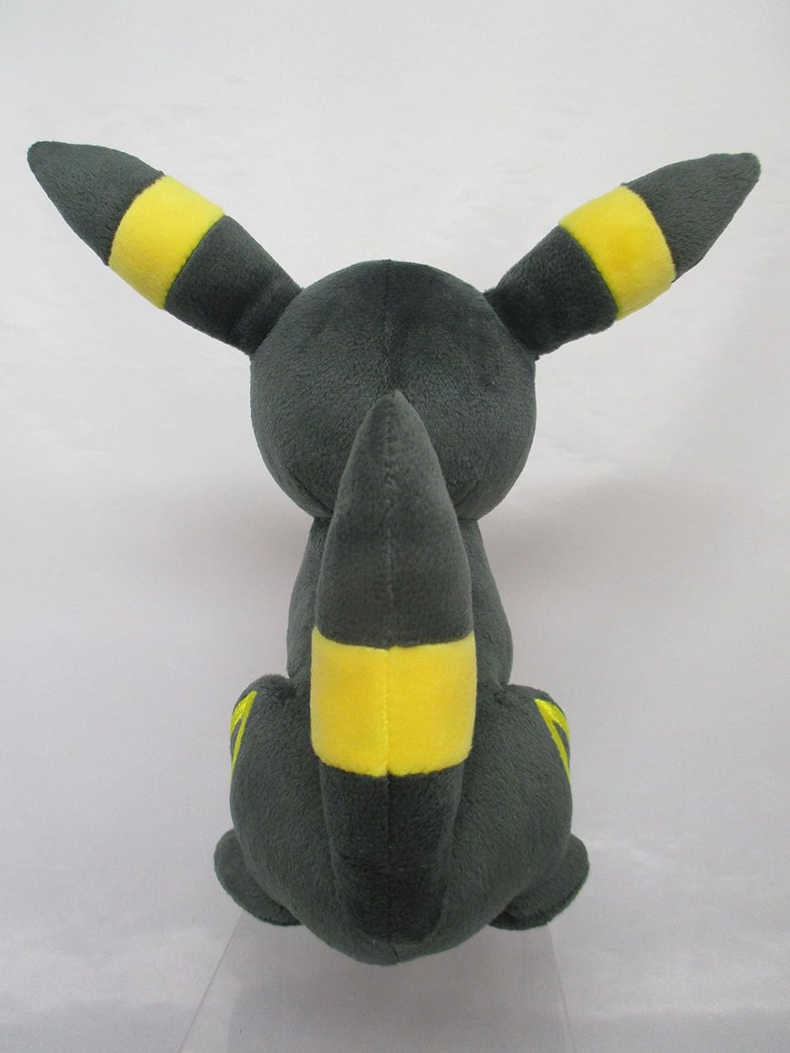 Dark grey Pokémon Umbreon plush toy viewed from the back, highlighting yellow-banded ears and tail
