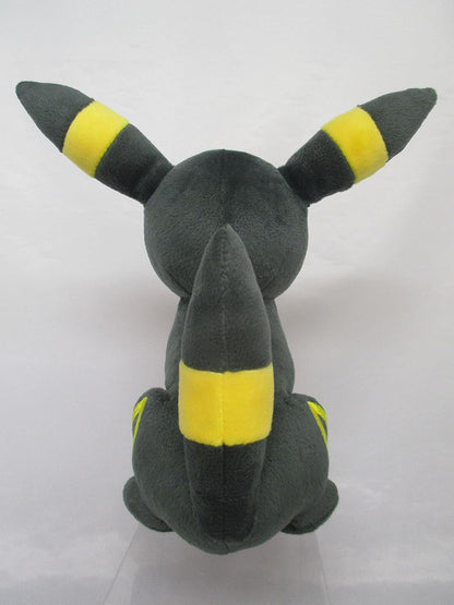 Dark grey Pokémon Umbreon plush toy viewed from the back, highlighting yellow-banded ears and tail