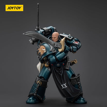 A JOYTOY action figure of a bald, teal-armored warrior holding a large sword across his chest