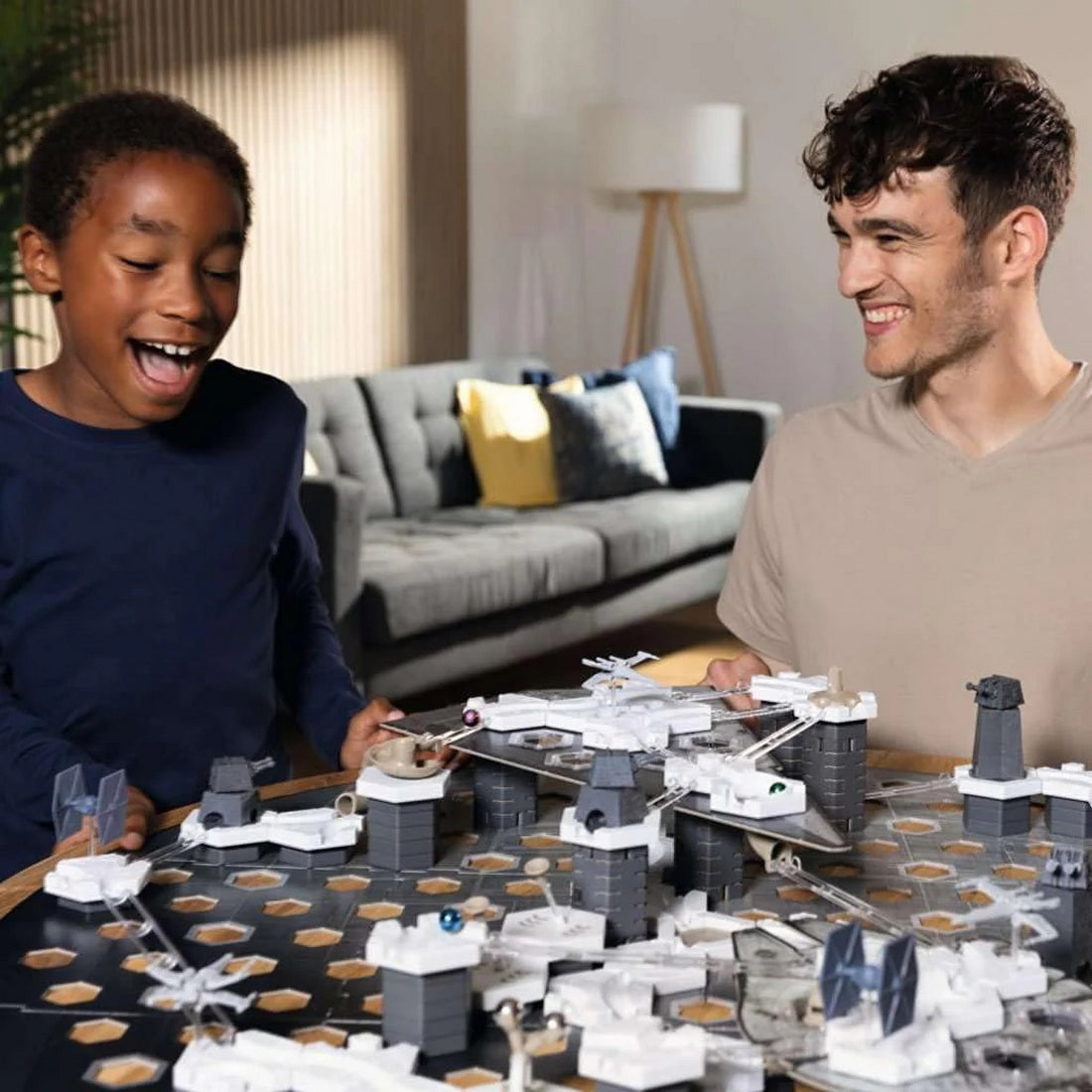 Smiling man and excited boy playing a Star Wars strategy board game with miniature ships