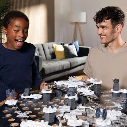 Smiling man and excited boy playing a Star Wars strategy board game with miniature ships