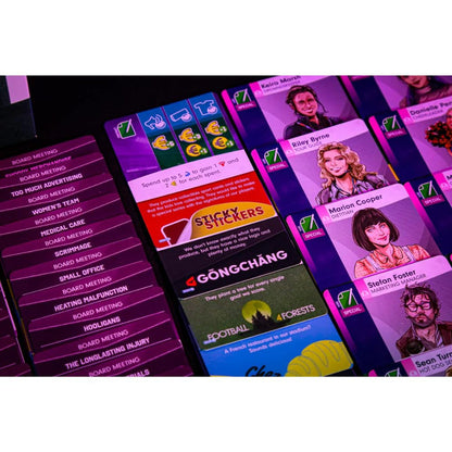 Close-up view of various gameplay cards from a board game set on a black table