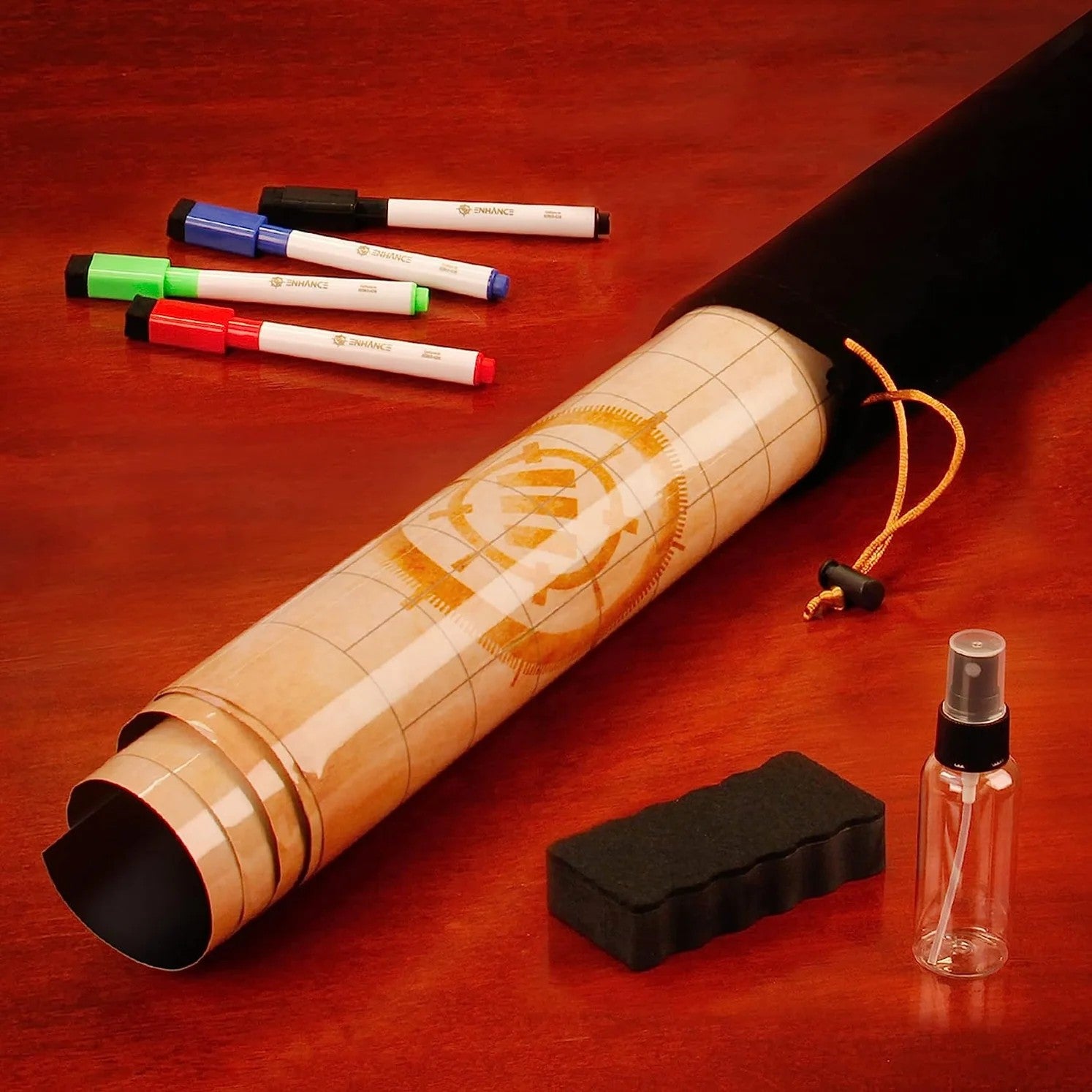 The Enhance Tabletop RPG Parchment Grid Mat Campaign Kit is displayed rolled in its black bag with four markers, an eraser, and a spray bottle