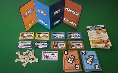 Pavlov's Dogs game elements including an open folder showing difficulty levels, multiple dog-themed cards, bone tokens, Beg and Roll action cards, and a rule book on green felt