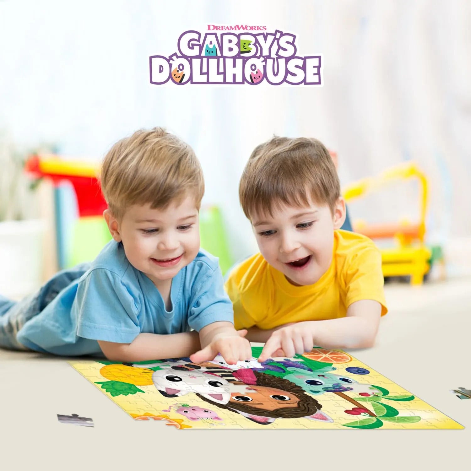 Two happy young boys lie on the floor, assembling a Gabby's Dollhouse puzzle.