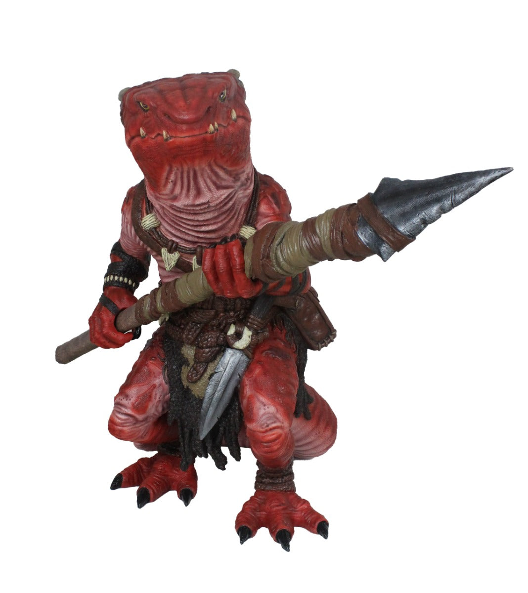 A red, bipedal reptilian kobold figure with sharp teeth and primitive clothing, holding a large spear