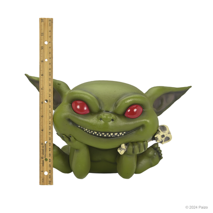 Green baby goblin figure with red eyes, sharp teeth, and pointed ears, sitting and holding a small skull