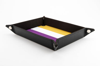 A rectangular black velvet dice tray featuring the yellow, white, and purple Nonbinary flag pattern on the interior base and silver corner snaps