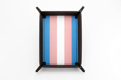 The Fanroll foldable dice tray featuring a dark brown exterior and a plush blue, pink, and white striped interior representing the Transgender Pride Flag