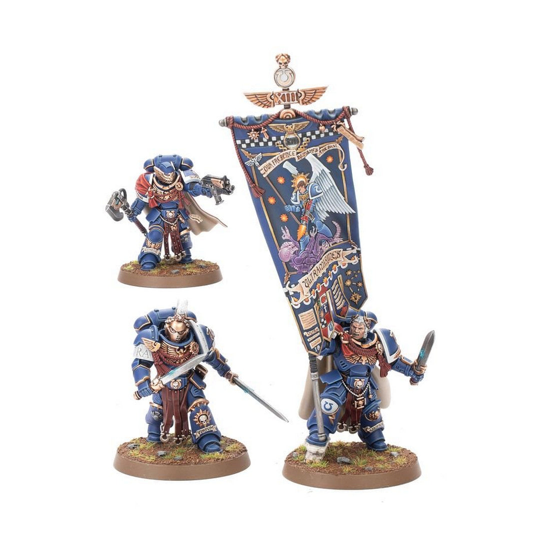 Three Ultramarines Space Marine miniatures, including a standard bearer with a large blue banner