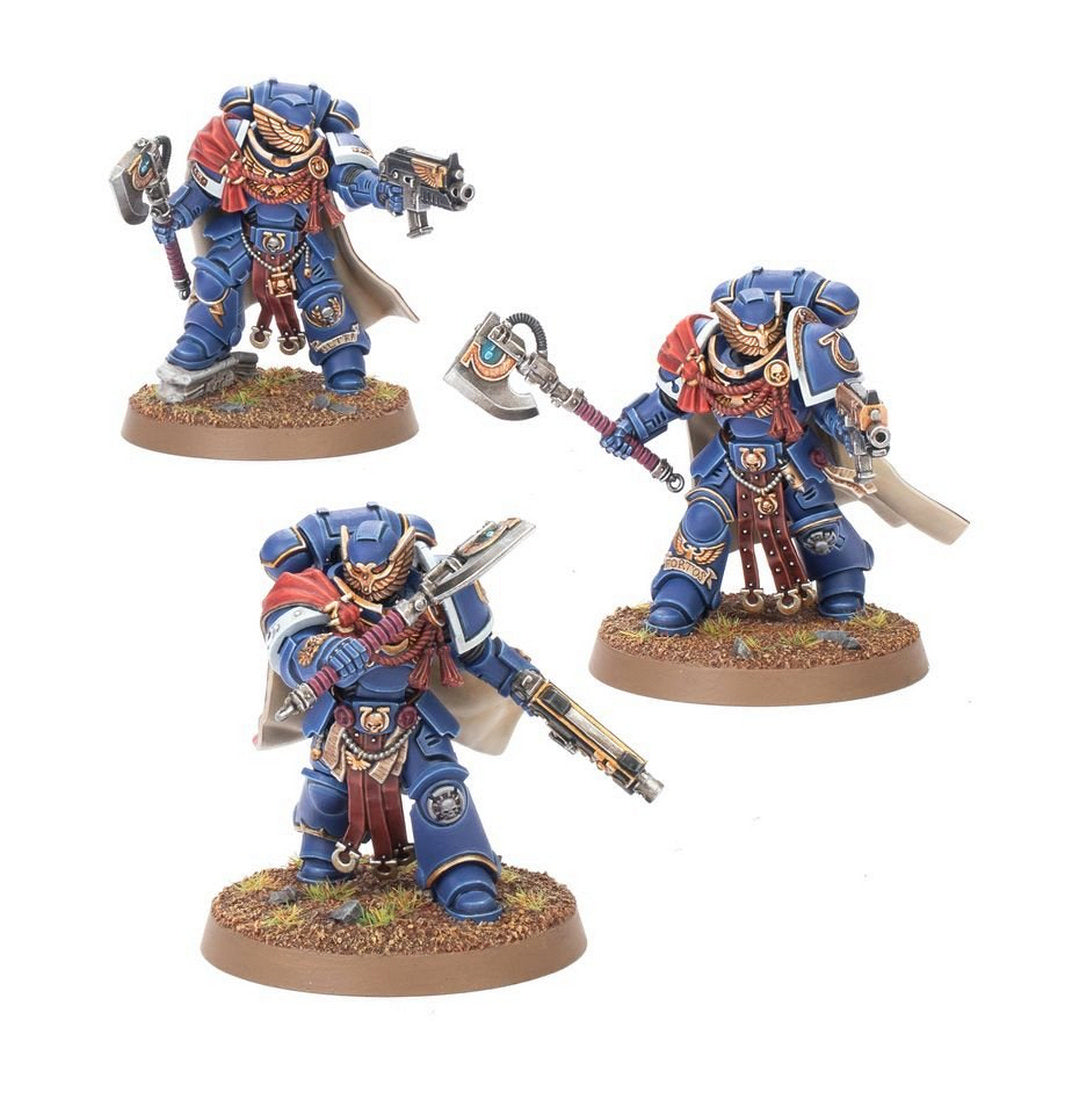 Three painted miniature Space Marine command figures in blue armor, holding power axes and guns