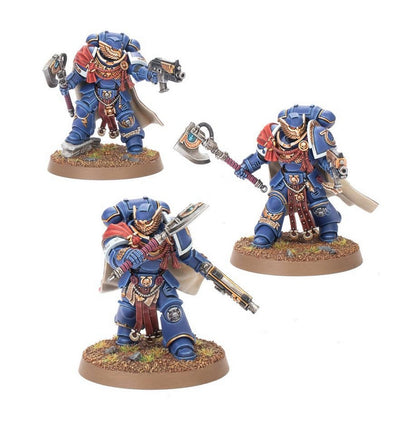Three painted miniature Space Marine command figures in blue armor, holding power axes and guns