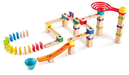 Modular wooden marble run kit showcasing elevated tracks, several moving marbles, a large red spiral funnel, and a rainbow sequence of standing dominoes