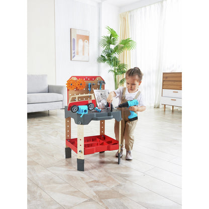A child stands at the red and gray toy vehicle service bench, which features a van motif, large gears, and holds a blue toy power drill