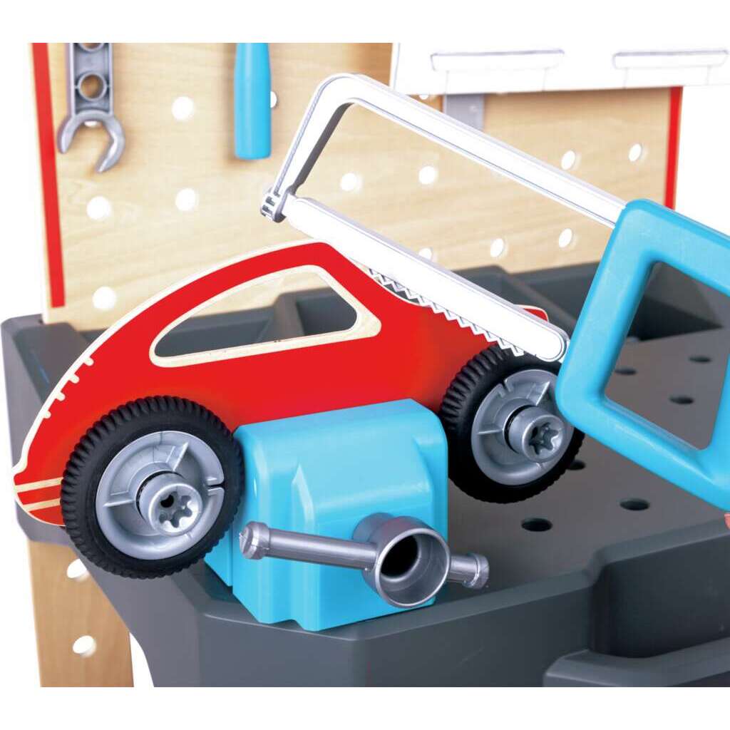 Wooden and plastic vehicle repair workbench detail showing a red car secured in a blue vise beneath a toy saw and near hanging tools