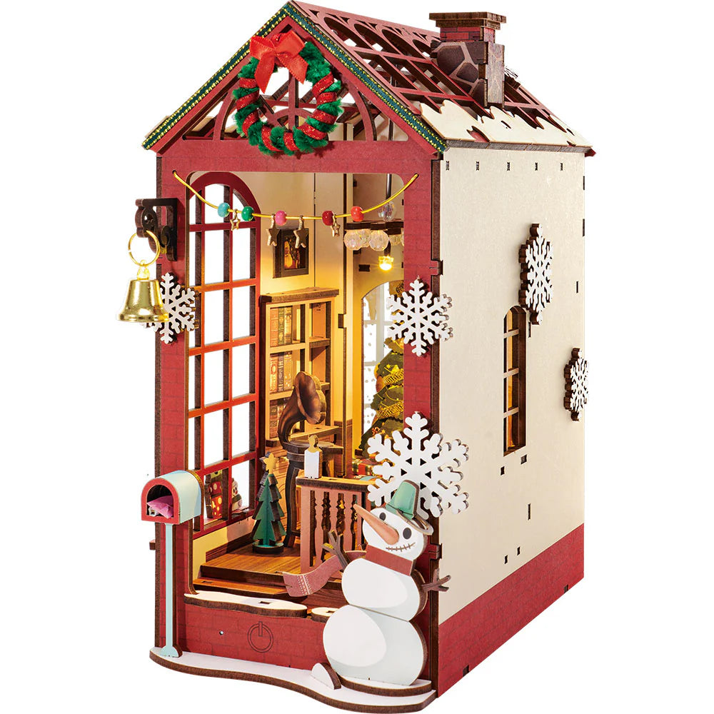 Detailed DIY Christmas bookend featuring a vertical slice of an illuminated house with a library, wreath, golden bell, and an exterior wooden snowman