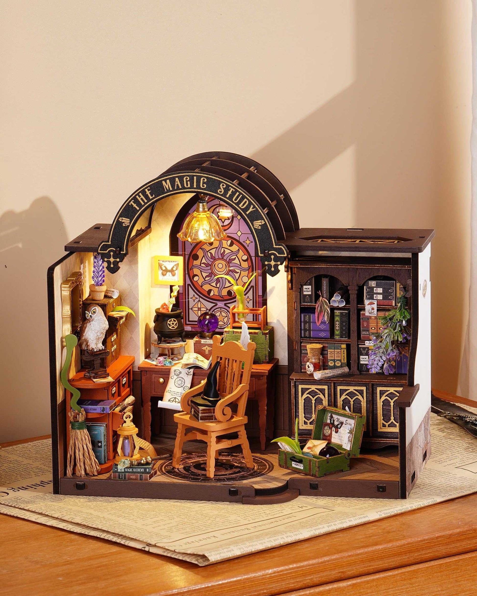 The assembled DIY Mini House kit displays "The Magic Study," a mystical scene complete with an enchanted desk, books of magic botany, a tiny owl, and a lighted arched window