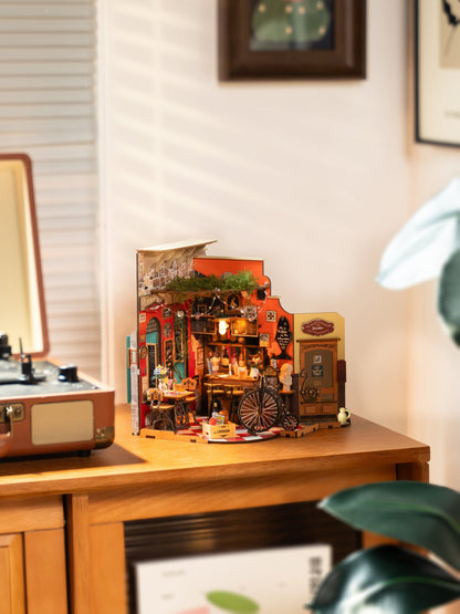 The assembled Diy Mini House Cheers Bar and Dining model showcases detailed furniture and brick textures illuminated by a warm interior light next to a record player