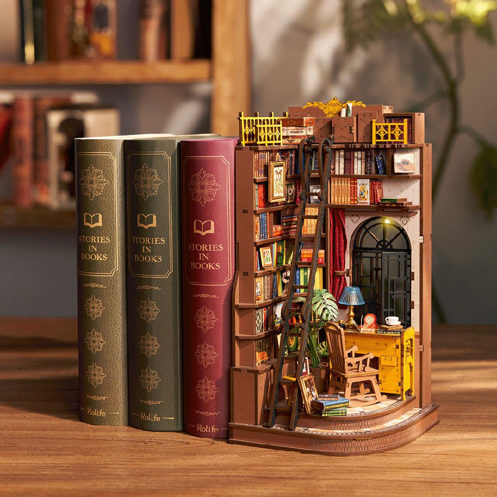 Illuminated DIY book nook featuring a silent corner study diorama with a tall bookshelf and ladder nestled against three ornate decorative books