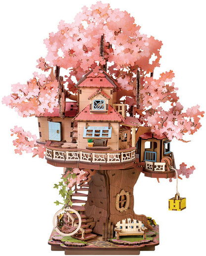 This intricate wooden 3D puzzle shows a cozy multi-level treehouse nestled among pink cherry blossoms with miniature furniture and winding exterior stairs