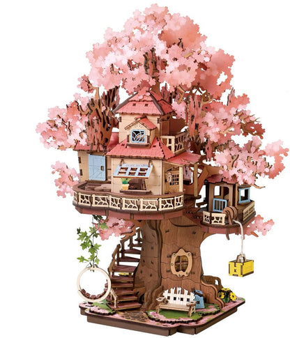 This wooden DIY miniature Sakura tree house features pink cherry blossoms, a detailed main cabin, a wrap-around balcony, stairs, and a small ground-level garden setting