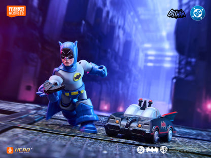 Dynamic toy shot of a blue-suited 1966 Batman action figure holding a batarang next to a miniature Batmobile