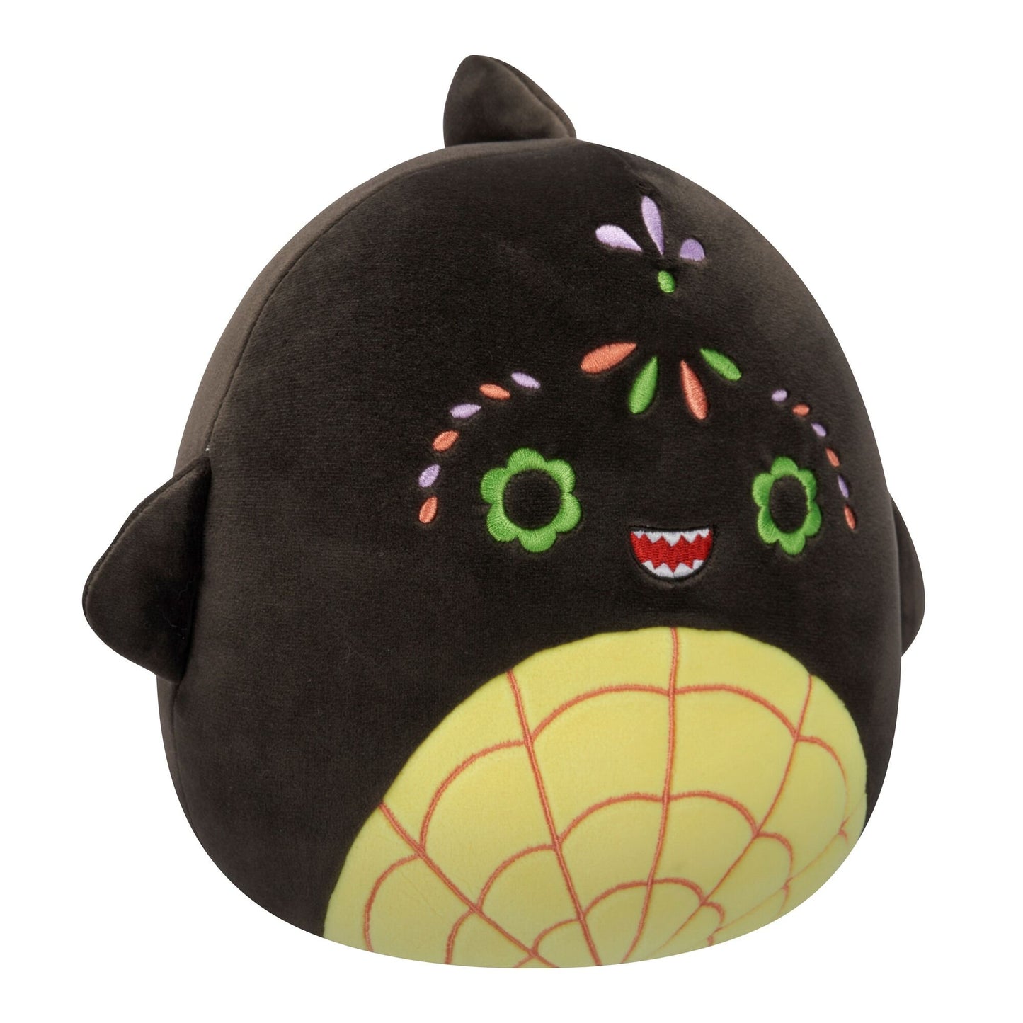 A black Squishmallow plush with green flower eyes, a toothy smile, colorful sugar skull-like embroidery, and a yellow spiderweb belly