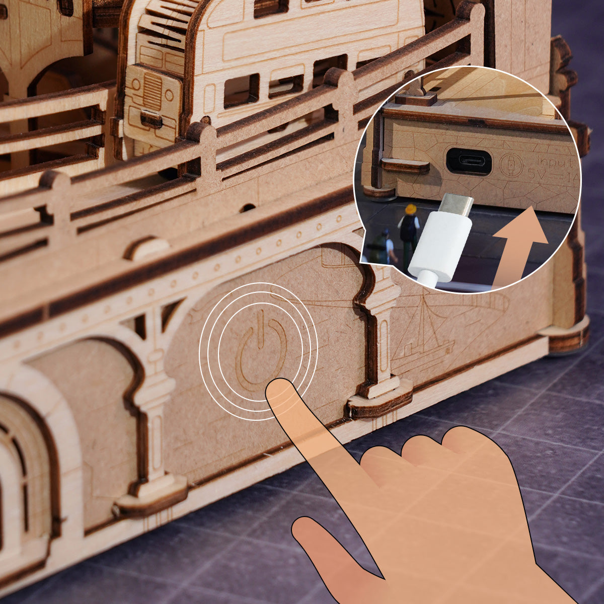 Finger activates wooden puzzle model's power button; inset shows USB-C charging port