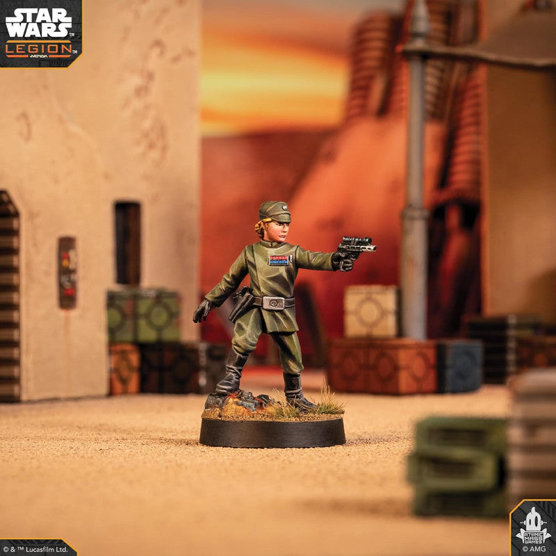 Imperial Officer miniature in a green uniform aims a pistol on a desert themed tabletop for Star Wars: Legion