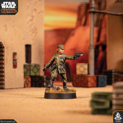 Imperial Officer miniature in a green uniform aims a pistol on a desert themed tabletop for Star Wars: Legion