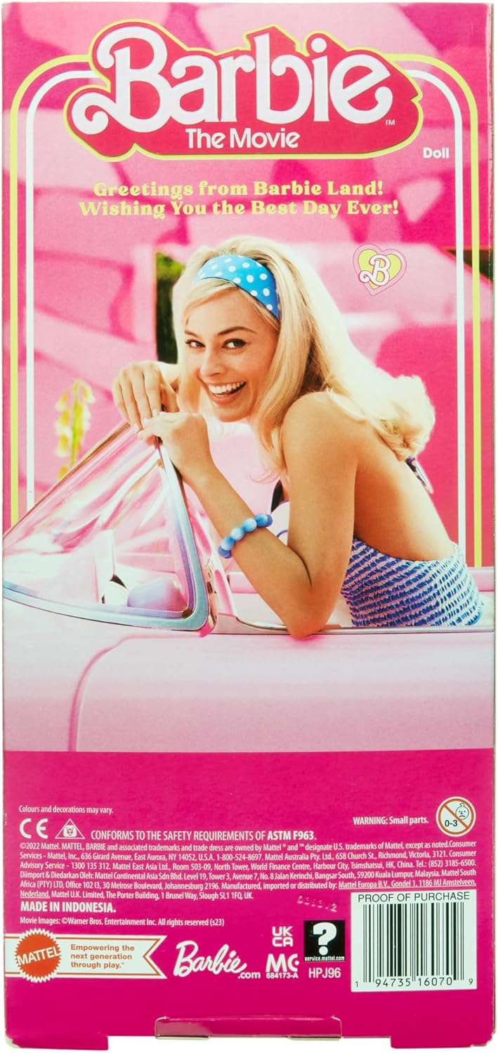 Barbie The Movie doll box featuring Margot Robbie as Barbie with blonde hair and a blue headband -  smiling -  leaning on a pink car