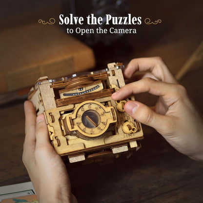 Hands manipulating the dials on an intricate wooden mechanical puzzle box shaped like a camera
