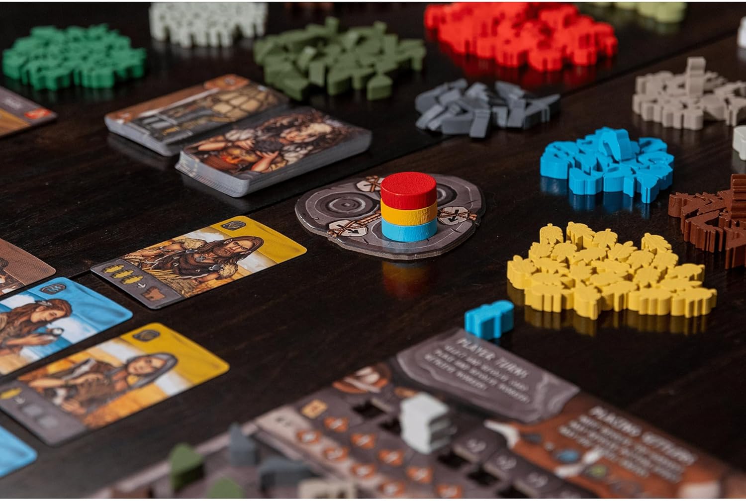 Colorful wooden meeples, resource piles, and illustrated character cards used in a strategic board game