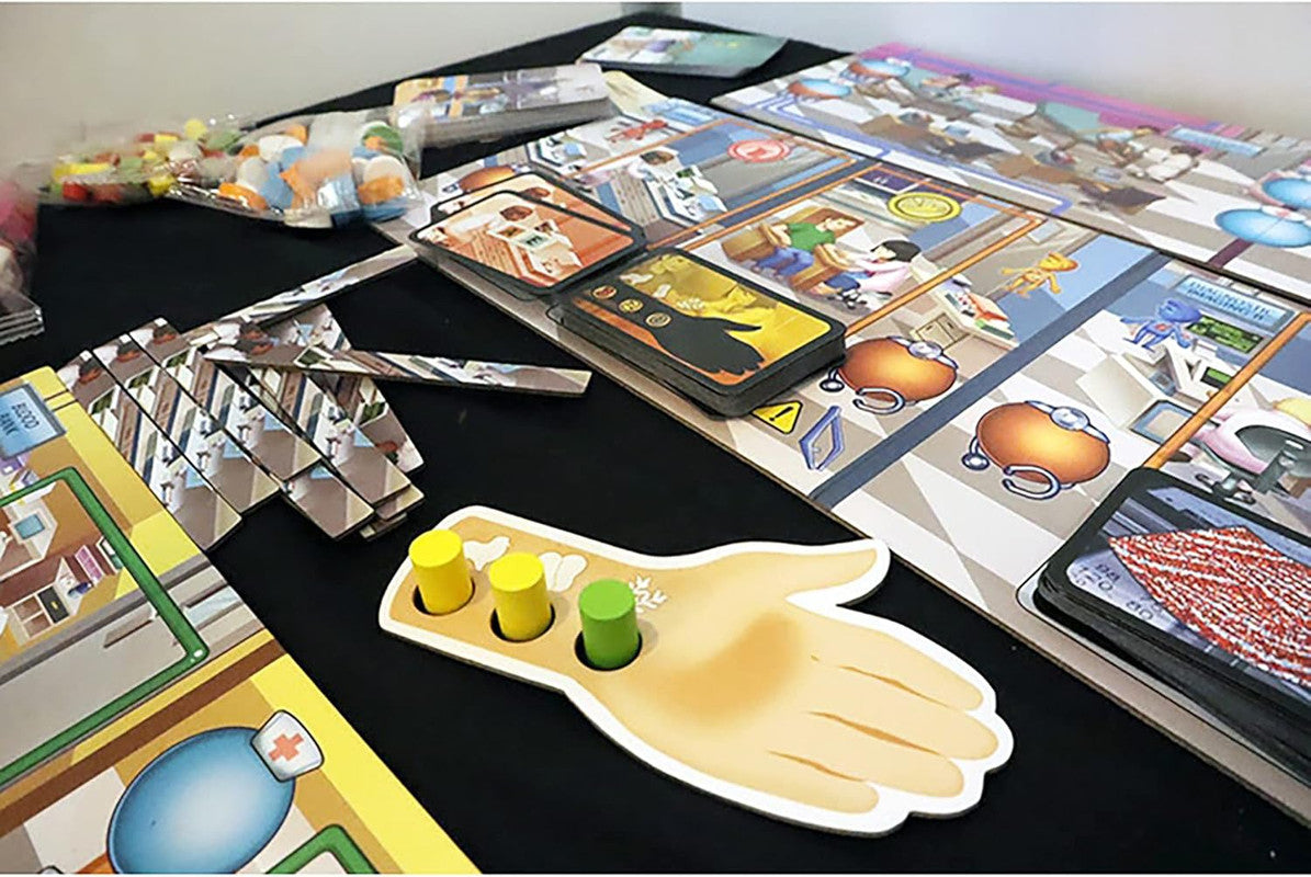 A Rush M.D.: ICU Expansion board game is laid out on a table, showing an illustrated board, stacks of cards, tokens, and a hand-shaped player piece with pegs