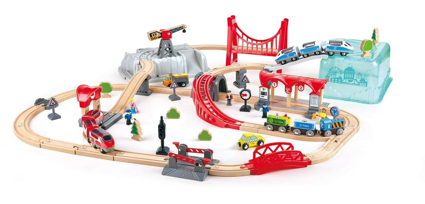 Detailed wooden toy train set with tracks, red bridges, a station, tunnel, crane, and several passenger and freight trains