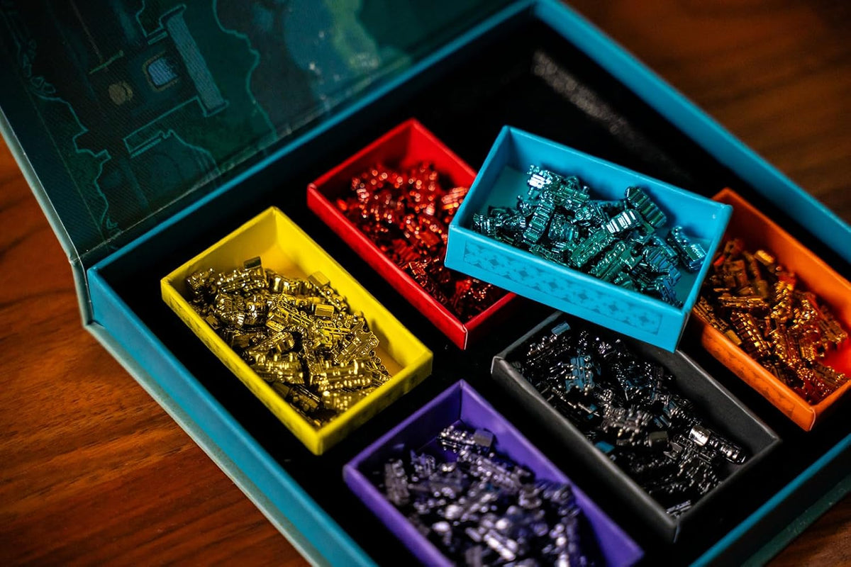 Open dark blue box displaying six colorful trays of metallic miniature train game pieces
